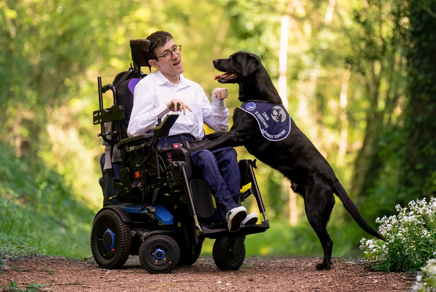 David, assis sur son fauteuil roulant, et Surfy, son chien d'assistance HANDI'CHIENS