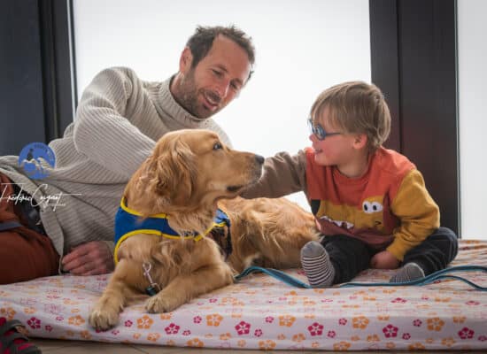 Un petit garçon regarde tendrement son chien d'éveil HANDI'CHIENS